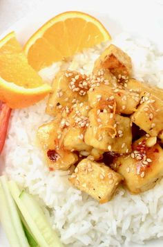 a white plate topped with rice and chicken next to an orange wedge on top of it