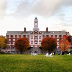 an old building with lawn chairs in front of it and trees on the other side