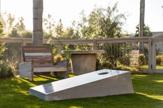 a concrete bench sitting on top of a lush green field next to a cement planter