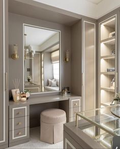 a dressing table with a mirror and stool in a room that has glass shelves on the wall