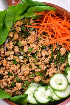 a salad with carrots, cucumbers and meat in a bowl on a table