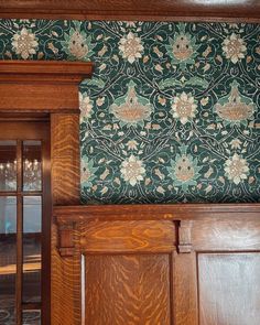 an ornate wallpapered room with wood paneling and wooden door frames in front of it