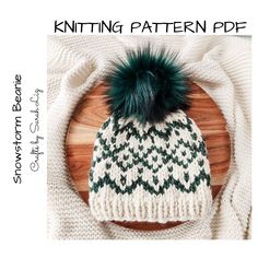 a knitted hat with a green pom - pom sitting on top of a wooden