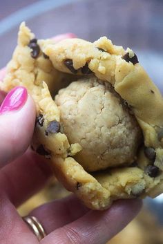 a hand holding a cookie in it's middle with chocolate chips on the inside