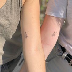 two people with matching tattoos on their arms, one holding the other's arm