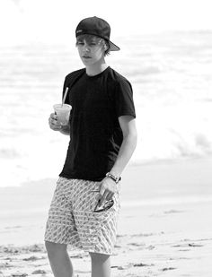 a man standing on the beach holding a drink