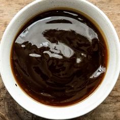 a white bowl filled with brown liquid on top of a wooden table