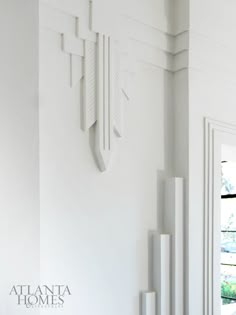 a clock mounted to the side of a white wall next to a window and door