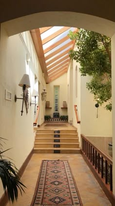 an entry way with stairs, potted plants and a rug on the floor in front of it