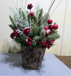 a potted plant with red berries and greenery in it sitting on a table