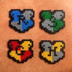 four pieces of perler bead art sitting on top of a table