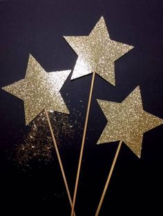 three gold glittered stars on top of sticks