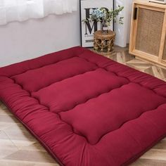 a red futon mattress on the floor