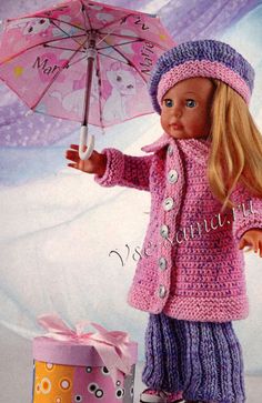 a doll holding an umbrella next to a gift box and a pink crocheted hat