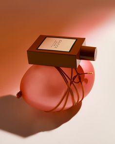 a pink vase with a brown box on it and a string attached to the base