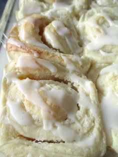 glazed donuts with icing sitting on a white plate next to a glass container