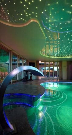 a large indoor swimming pool with lights on the ceiling and water running down it's sides