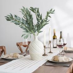 a dining room table set with plates, glasses and wine bottles on top of it