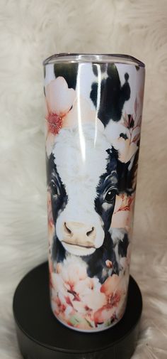 a cow with flowers painted on it's face is sitting on a black stand