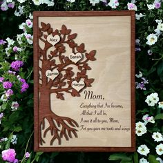 a wooden plaque with the names of two people and a tree on it in front of flowers