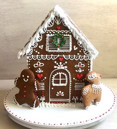 a gingerbread house is decorated with icing and decorations on a white platter