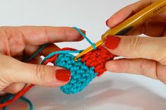 two hands are crocheting together to make a small piece of blue and red yarn