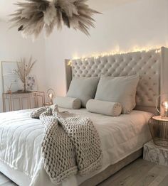 a white bed with pillows and blankets on top of it, surrounded by string lights