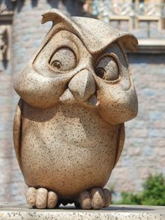 an owl statue sitting in front of a castle