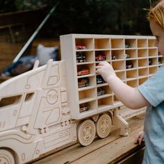 a young boy playing with a wooden toy truck