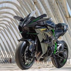 a black and green motorcycle parked in front of a building