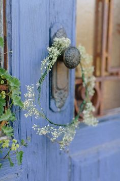 a blue door with a wreath on the handle and flowers hanging from it's side