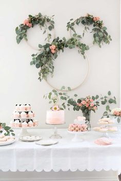 a table topped with cakes and desserts covered in greenery