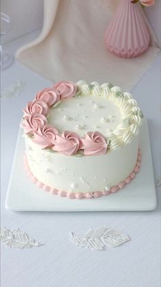 a white cake with pink icing on a table