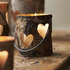 a candle with two hearts on it sitting in front of a tree stump and some candles