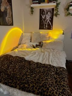 a leopard print blanket on a bed with yellow light coming from the headboard and foot board