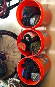 three orange cups are hanging on the wall next to a bicycle tire and other items