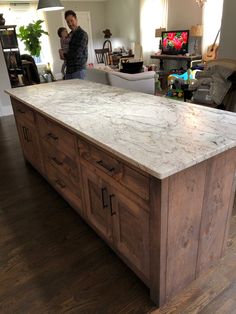 a man standing in the middle of a kitchen with an island made out of wood