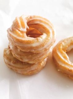 a stack of glazed donuts sitting on top of a white tablecloth next to each other