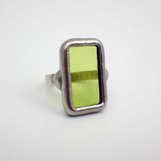 Small, transparent lime green stained glass ring edged in silver. The sterling silver wire band is size 6. This is a one of a kind ring.  Ring Size: US 6 / UK M Center Glass Size: 7/8" x 1/2" Each item by Faerie Glass is 100% uniquely hand-crafted with quality materials that are lead-free. NOTE - All photographs are taken in effort to best represent the actual product. Color of actual jewelry may vary slightly from photographs. Green Modernist Ring As A Gift, Modernist Green Ring For Gift, Green Modernist Ring As Gift, Unique Green Rectangular Rings, Modern Green Ring With Rectangular Stone, Modernist Green Ring As A Gift, Modernist Green Rings For Gift, Modern Green Rectangular Stone Ring, Handmade Green Rectangular Ring