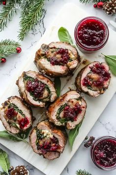 sliced turkey with cranberry sauce on a white platter next to pine cones