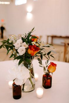 three vases with flowers and candles on a table