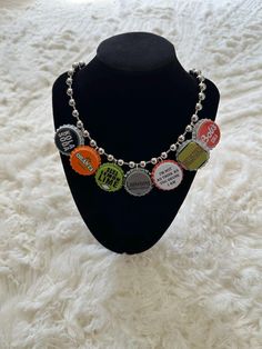 a black mannequin wearing a necklace with different colored buttons and words on it