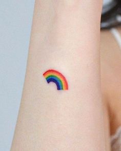 a small rainbow tattoo on the wrist is shown in this close up photo, it appears to be colorful