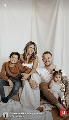 a man, woman and two children are posing for a family photo in front of a white backdrop