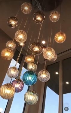 a chandelier made out of glass balls hanging from the ceiling in front of a window