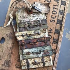 an old suitcase is hanging on a wooden plank with rope and tags attached to it