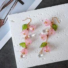 pink flowers and green leaves are hanging from gold - plated earwires on a white card