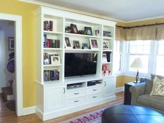 a living room filled with furniture and a flat screen tv on top of a white bookcase