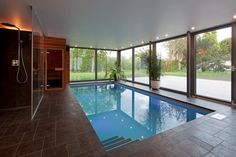 a large indoor swimming pool with glass doors leading to an outside shower area and hot tub