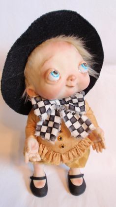 a doll with blue eyes wearing a black hat and scarf on top of it's head